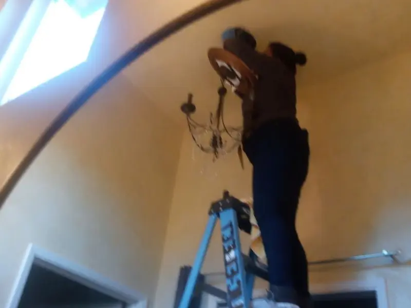 Electrician installing a chandelier in a Highlands residence